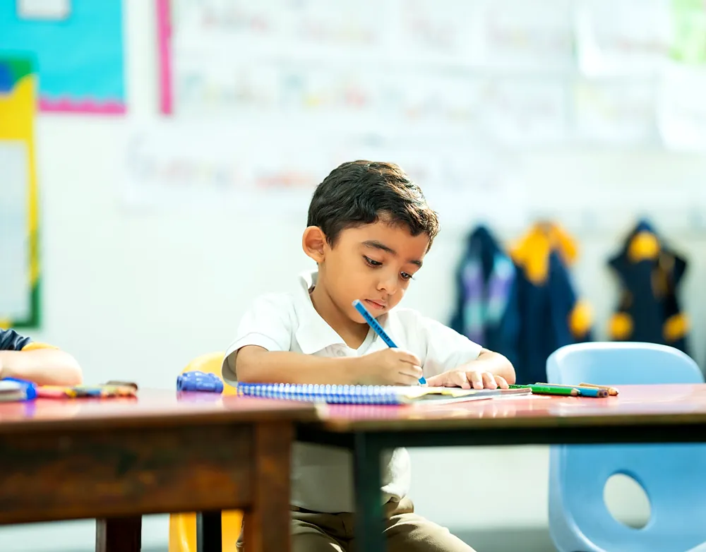 Niño de preescolar escribiendo en su cuaderno