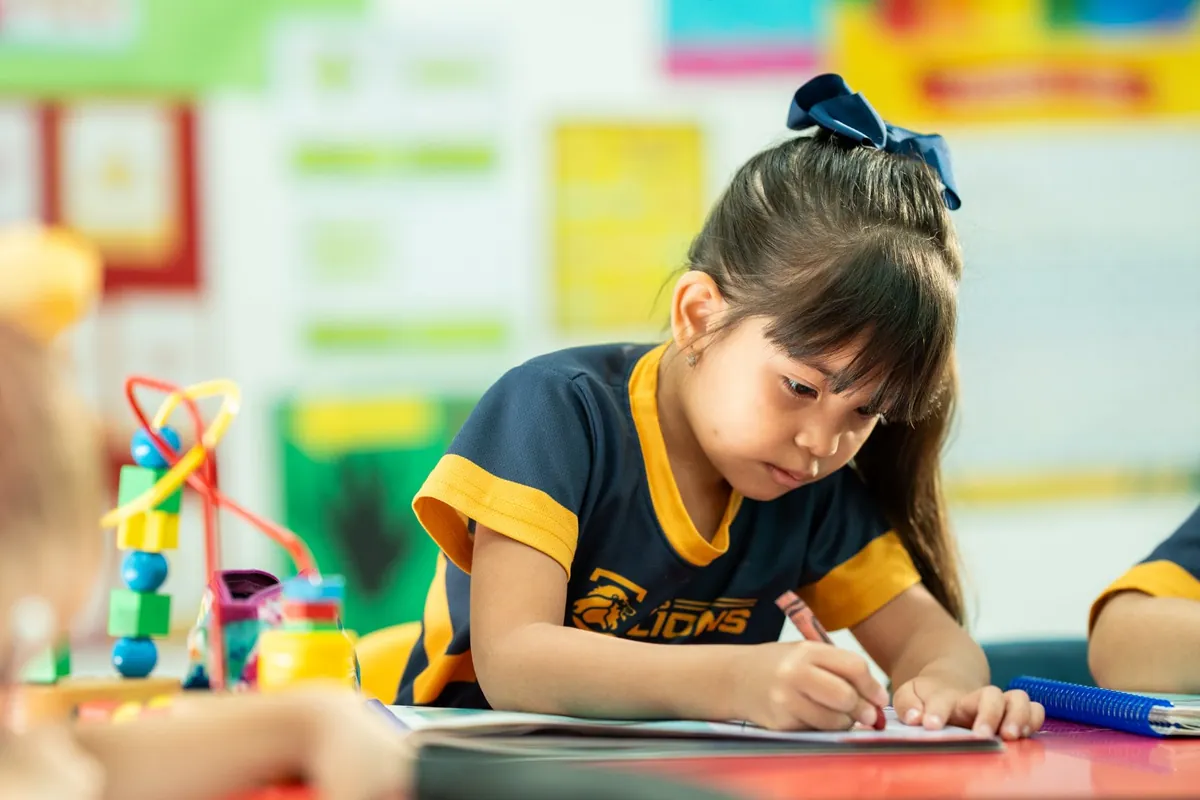 Niña de preescolar coloreando en clase